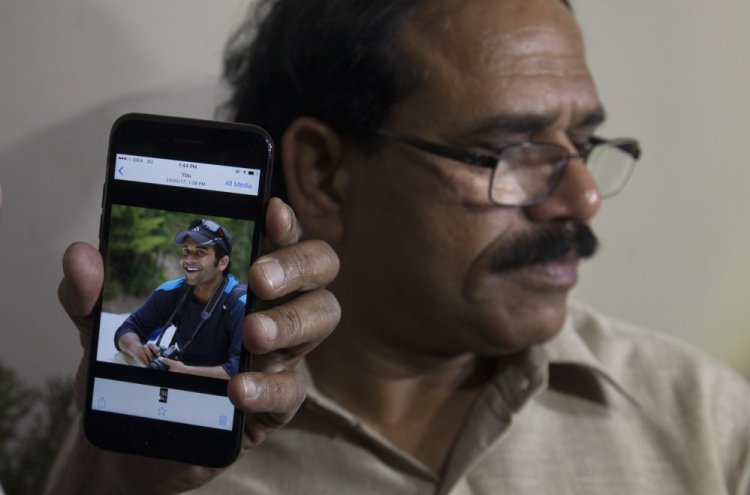 A man shows a picture of Alok Madasani, an engineer who was injured in the shooting Wednesday night in a crowded suburban Kansas City bar, on a mobile phone as Madasani's father, Jaganmohan Reddy, talks to the media at his residence in Hyderabad, India, on Friday.