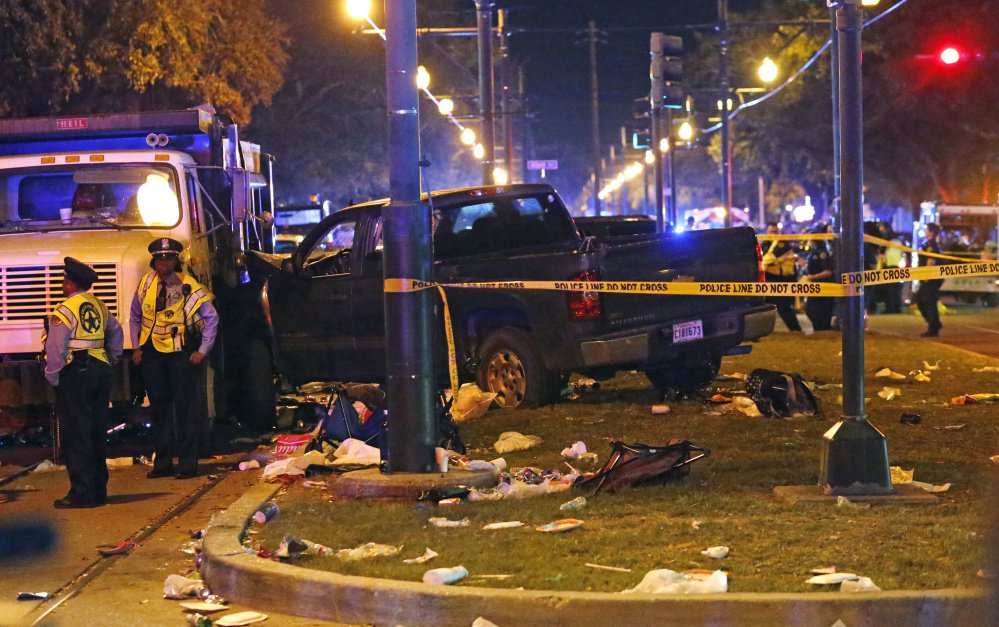 Police stand next to a pickup truck that slammed into a crowd, causing multiple injuries, before coming to a stop against a dump truck during a Mardi Gras parade in New Orleans.