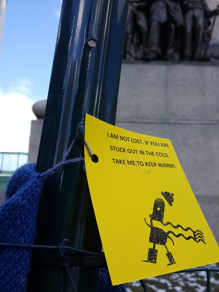 A hat sits attached to a fence in Monument Square on Friday with a note that encourages those in need to take the hat.   James Patrick/Staff Photo
