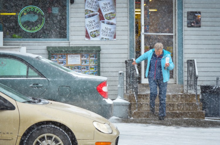 A woman carefully navigates the steps Wednesday at Christy's Market in Belgrade after stopping for a cup of coffee. Snow during Wednesday's morning commute made some roads slick, leading to accidents around the area.