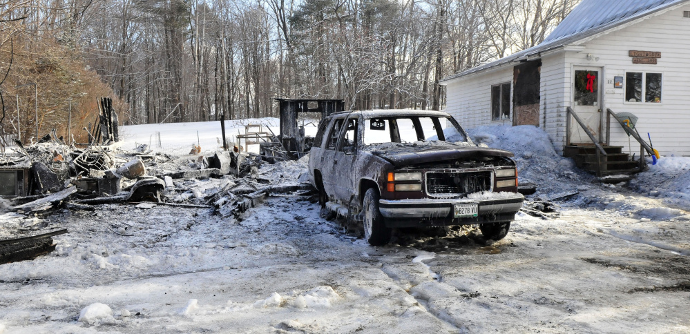Charred remains lie on the spot Thursday where a garage stood until it and its contents, as well as the Chevrolet Suburban in the foreground, burned Wednesday night at a home on Young Street in Madison.