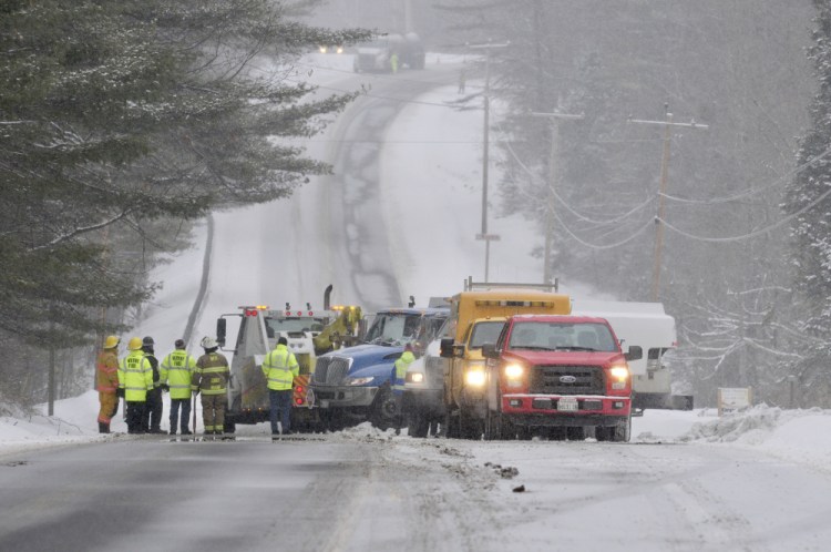 Wayne and Readfield firefighters, along with the Maine State Police, the Maine Department of Transportation and the Maine Department of Environmental Protection, work on Tuesday at the scene where an oil truck that overturned is being flipped back onto its wheels on Route 133 in Wayne.