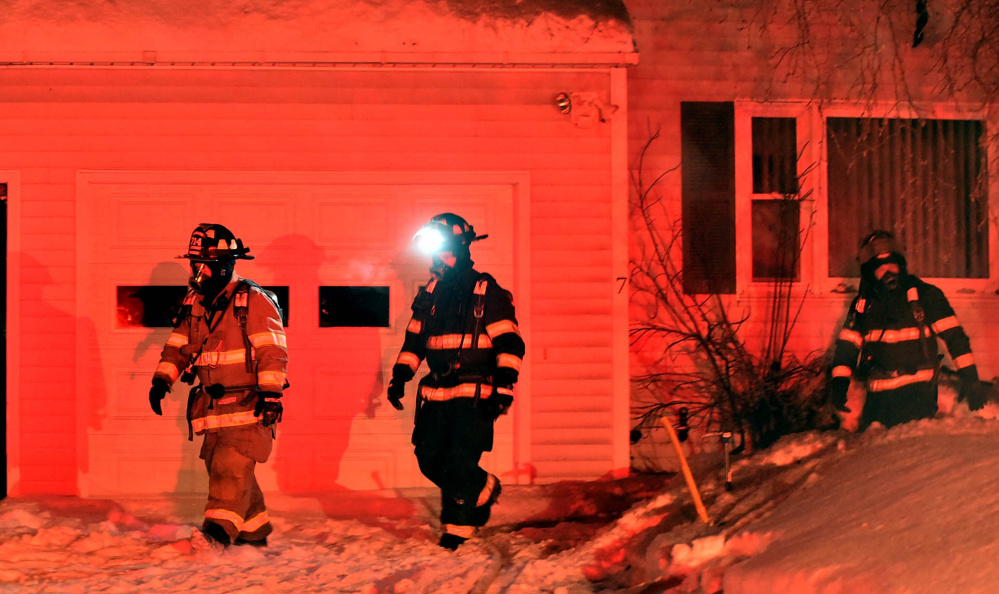 Firefighters look for remnants of a small house fire Saturday evening on John Avenue in Waterville.