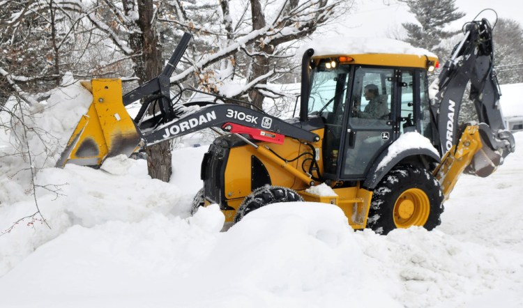 Jared Clukey of the Jordan Lumber company uses a bucket loader to pile up snow at a residence in Kingfield on Sunday to make room for the forecast 2 feet of snow expected to fall through Tuesday.