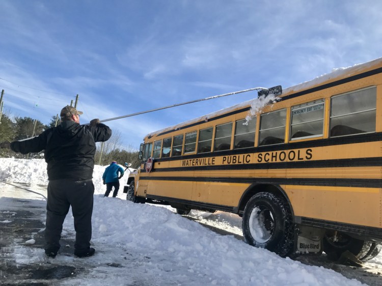 Larry Brown, of Waterville, a school bus driver for Alternative Organizational Structure 92, helps rake snow off the roof of a Waterville public schools bus Tuesday morning at Waterville Junior High School off West River Road. AOS 92 canceled school Tuesday, a day after a big snowstorm brought 2 feet of snow and blizzard conditions to the area.