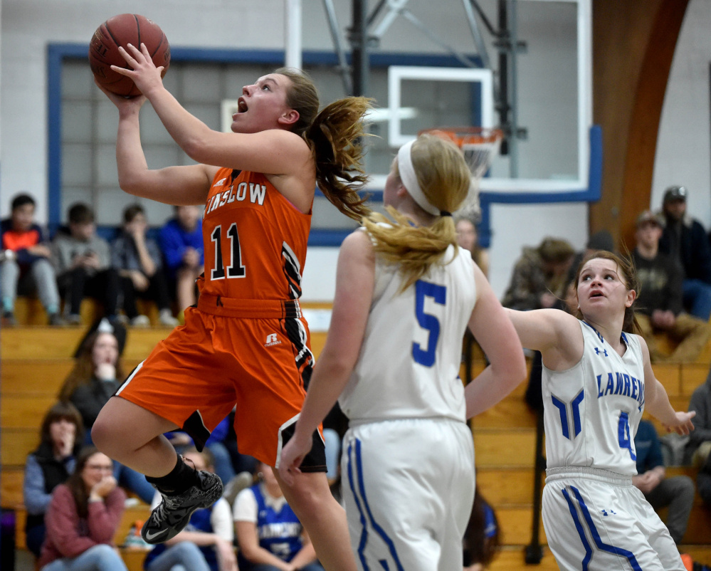 Winslow senior forward captain Heather Kervin (11) drives to the basket in front of Lawrence defender Brooklyn Lambert during the first quarter of a Kennebec Valley Athletic Conference game in Fairfield.