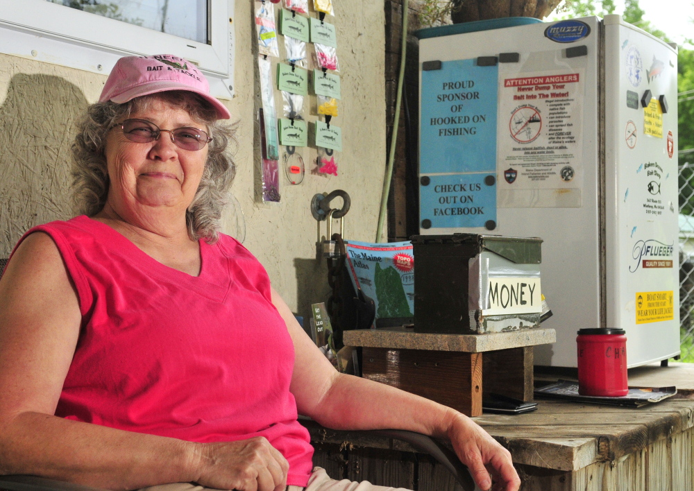 June Bubier sits beside a self-serve refrigerator full of bait in July 2014 on the porch at Bakers Dozen Bait Shop, the store in Winthrop that she owned with her husband David. Bubier was selected Tuesday night to serve on the Winthrop Town Council as a short-term replacement for her husband, who died in January.