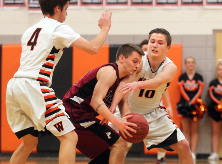 Winslow High School's Michael Wildes, right, tries to steal the ball from Maine Central Institute's Josh Buker as Spencer Miranda looks on during the first half of a Class B North prelim game on Thursday night in Winslow.