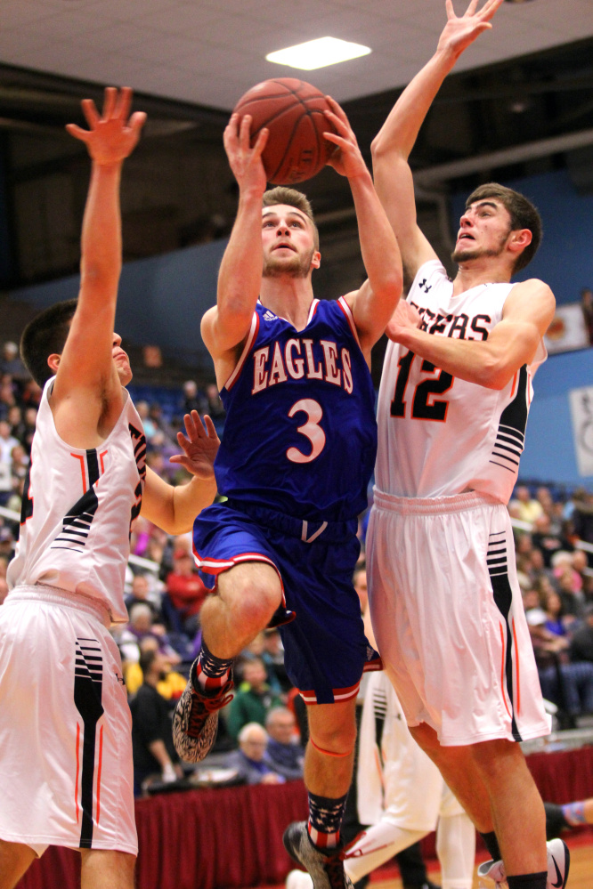 Messalonskee High School's Charles Dawson tries to split Gardiner Area High School's Hunter Chasse, left, and Connor McGuire, right, on a drive to the basket in the first half of a Class A North quarterfinal in Augusta on Saturday night.