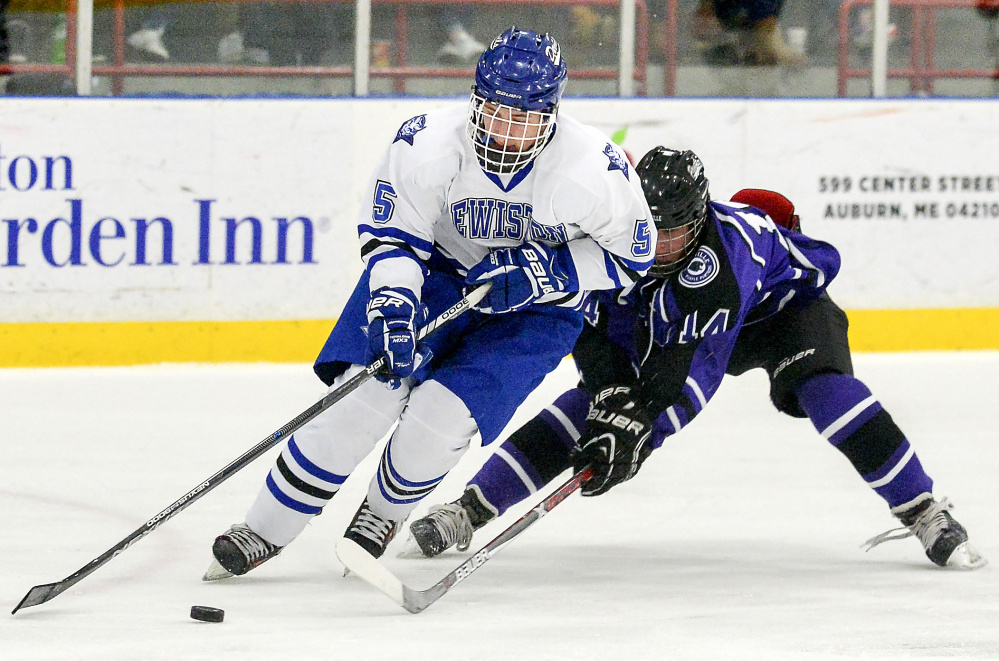 Michael Bolduc fights for control of the puck with Lewiston's Sam Story in the first period of their game Tuesday night in Lewiston.