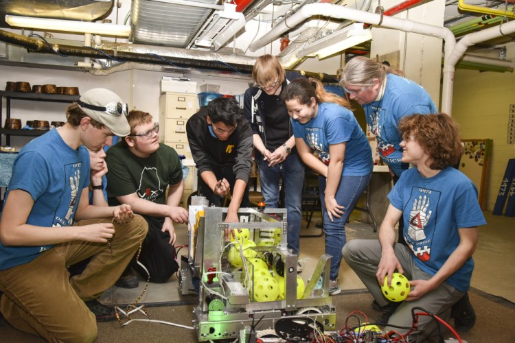 Hall-Dale High School students, all members of Delta Prime Robotics, huddle around their robotic entry Tuesday at the Ballard Center in Augusta with mentor Karen Giles, second from right, in order to finish their work before the competition deadline. The students are, from left, Kieran Dionne, Eli Spahn, Michael Crochere, Ean Smith, Bryce Bradgon, Alicia Warren and, at far right, team business and coding captain William Fahy.