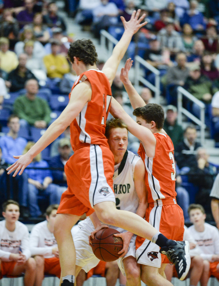 Winthrop's Jacob Hickey gets smashed between North Yarmouth Academy defenders Jake Malcom, left, and Davis Newell in the first quarter of the Class C South semifinal Thursday at the Augusta Civic Center.