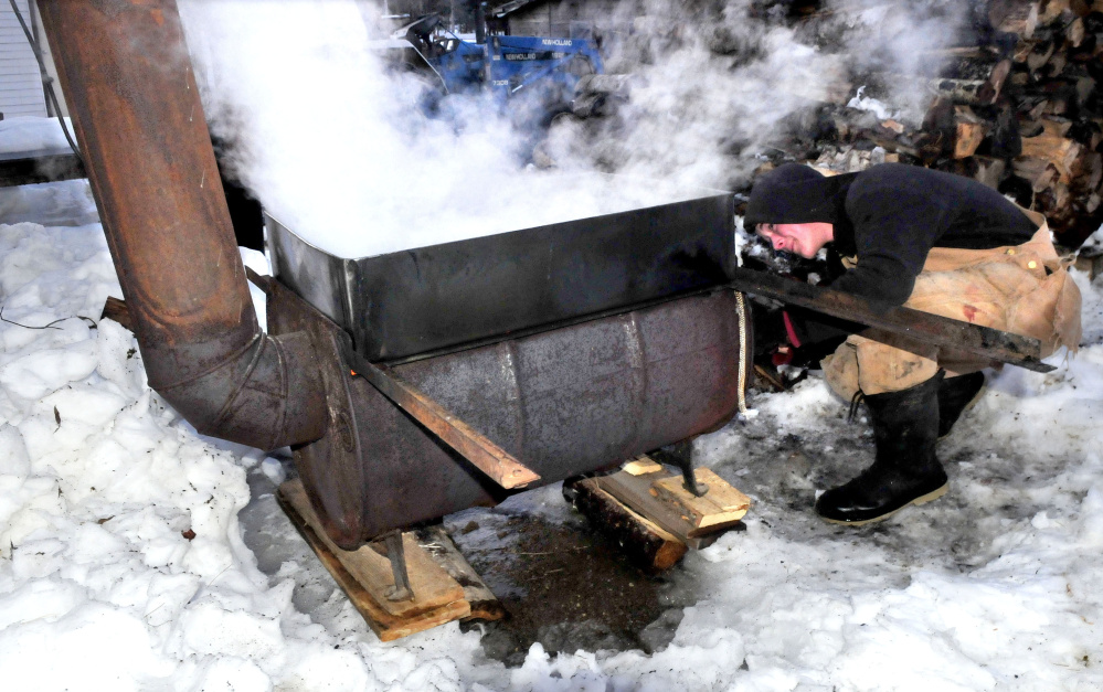 Steam rises as Addison Astbury stokes an evaporator with wood while boiling down maple sap into syrup at his home in Troy on Wednesday. Astbury said he has collected fast dripping sap for two warm days this week before beginning boiling.