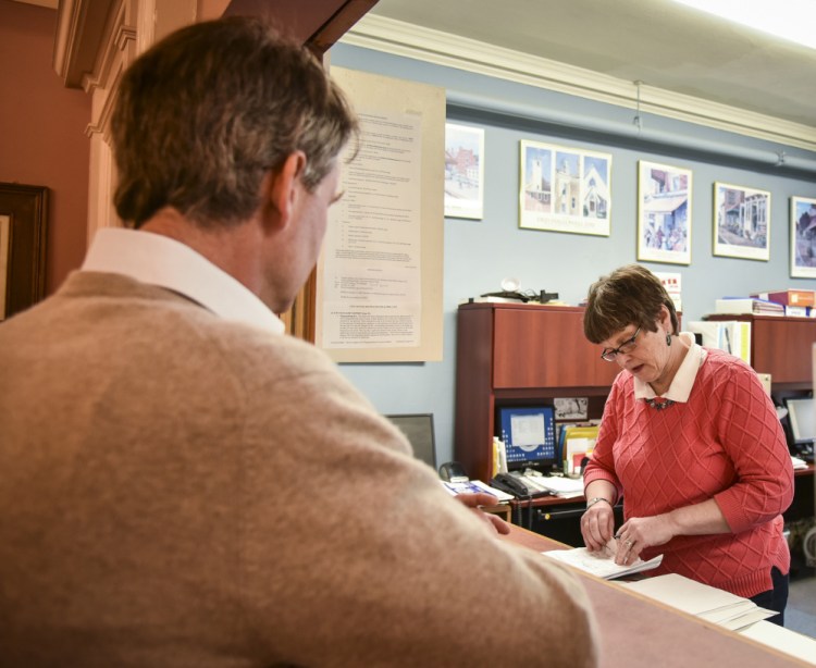 Hallowell City Clerk Diane Polky, right, inspects the petition just handed to her Friday by Stephen Langsdorf. He collected 288 signatures, 72 more than required, on a petition in an effort to force City Council to reconsider its decision on the future of city fire services.