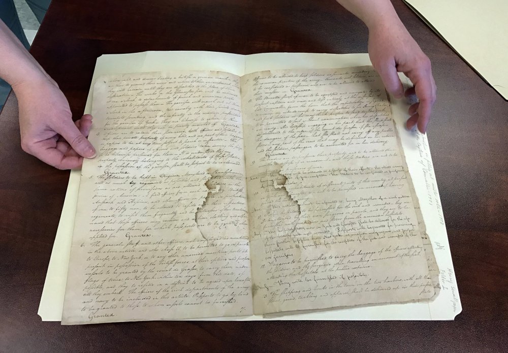 Archivist Heather Moran displays a 1781 copy of the "Articles of Capitulation," which lays out the terms of British surrender after the Battle of Yorktown. The document is one of hundreds in the collection of the Maine State Archives that are awaiting transcription.