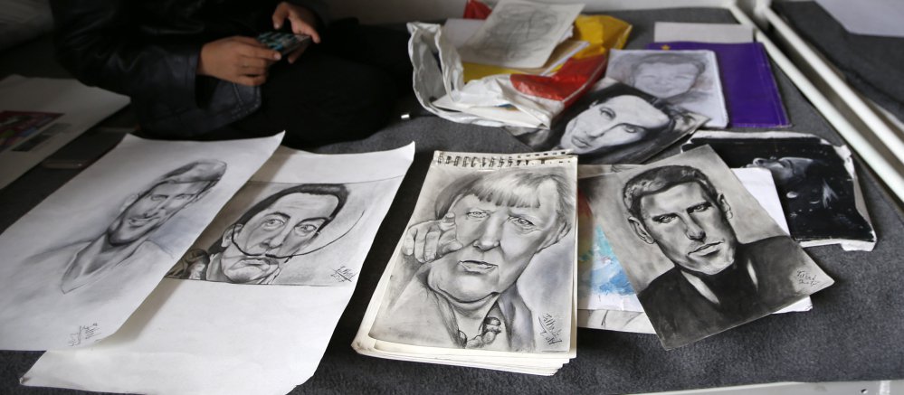 Farhad Nouri displays his portraits of Serbian tennis player Novak Djokovic, left, Spanish surrealist painter Salvador Dali, second from left, and German Chancellor Angela Merkel, third from left, in his family's room at a refugee camp near Belgrade, Serbia, on Monday.