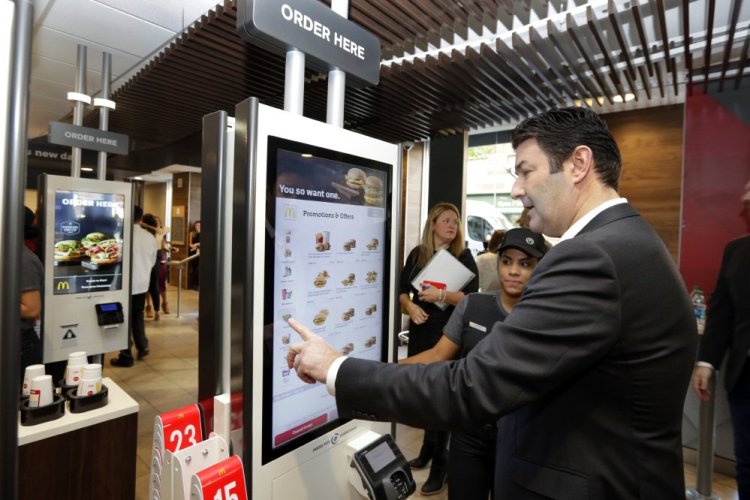 McDonald's CEO Steve Easterbrook demonstrates an order kiosk, with cashier Esmirna DeLeon, during a presentation at a McDonald's restaurant in New York's Tribeca neighborhood last November. McDonald's has started testing mobile order-and-pay after acknowledging the ordering process in its restaurants can be "stressful." The company is also introducting ordering kiosks, which it says can help ease lines at the counter and improve order accuracy.