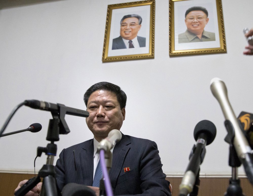 Pak Myong Ho, minister of the North Korean Embassy in China, sits under portraits of the late North Korean leaders Kim Il Sung, left, and Kim Jong Il, on Thursday as he warns the West that North Korea is prepared to act in self-defense.