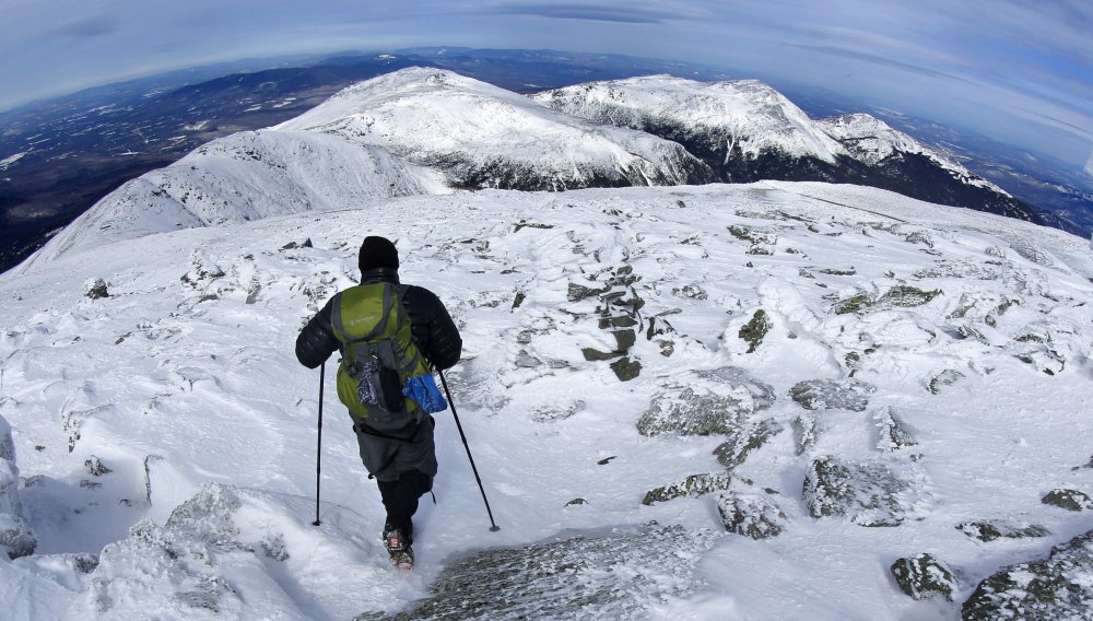 A hiker leaves the summit of Mount Washington in New Hampshire earlier this month. The snow-covered peaks of the northern Presidential Range can be seen in the distance.