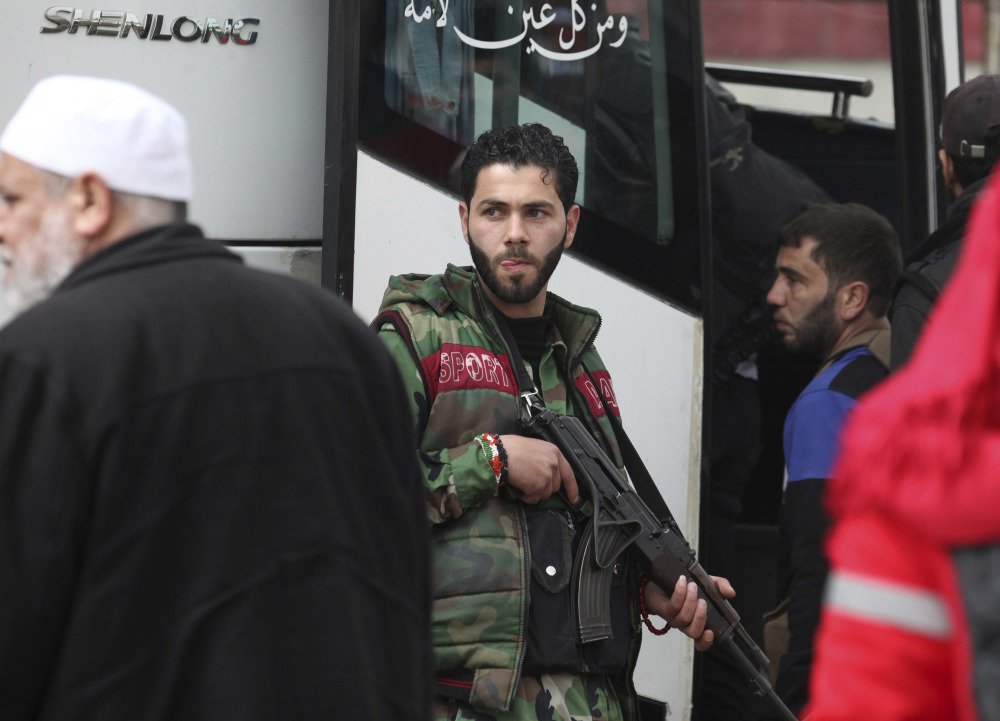 Rebel gunmen carrying their weapons leave the al-Waer neighborhood in Homs, Syria, bound for a town on the Turkish border on Saturday.