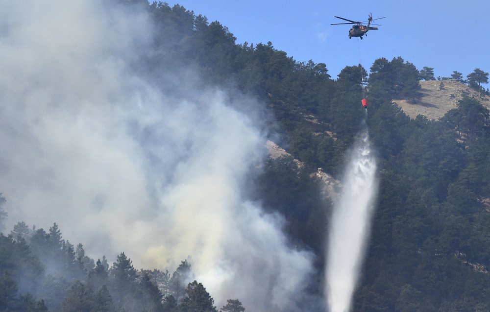 A helicopter drops water on the fire burning west of Boulder, Colo., on Sunday. The fire forced people from hundreds of homes early Sunday, authorities and residents said.