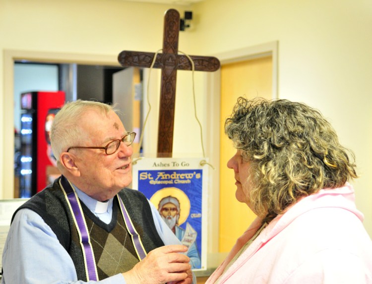 The Rev. James Gill chats with Theresa Edwards before marking a cross with ashes on her forehead on Wednesday at the Winthrop Commerce Center.