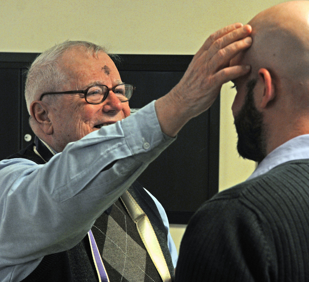The Rev. James Gill applies ashes to the Stephen Farrington's forehead Wednesday at the Winthrop Commerce Center. Gill was marking people with a small cross in ashes as part the international Ashes To Go program on Ash Wednesday, the beginning of the Christian season of Lent, which leads up to Easter.