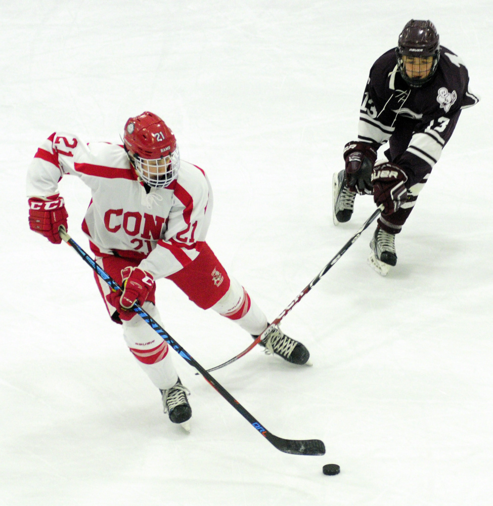 Cony's Thomas Arps, left, skates ahead of Edward Little's Cam Audette during a Class A North quarterfinal Tuesday at Camden National Ice Vault in Hallowell.