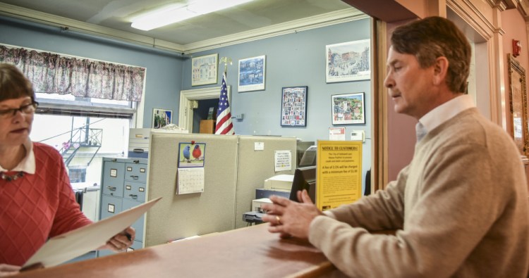 Hallowell City Clerk Diane Polky, right, inspects a petition just handed to her Feb. 24 by Stephen Langsdorf. Polky determined this week that Langsdorf got enough signatures to force the City Council to reconsider its fire services decision.