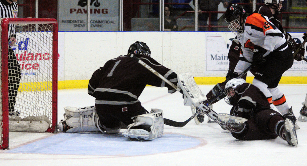 Greely goalie Josh Lawless, left, and defenseman Ben Kennedy block a shot by Gardiner forward Jacob Folsom in a Class B South semifinal game Friday night at the Androscoggin Bank Colisée in Lewiston.