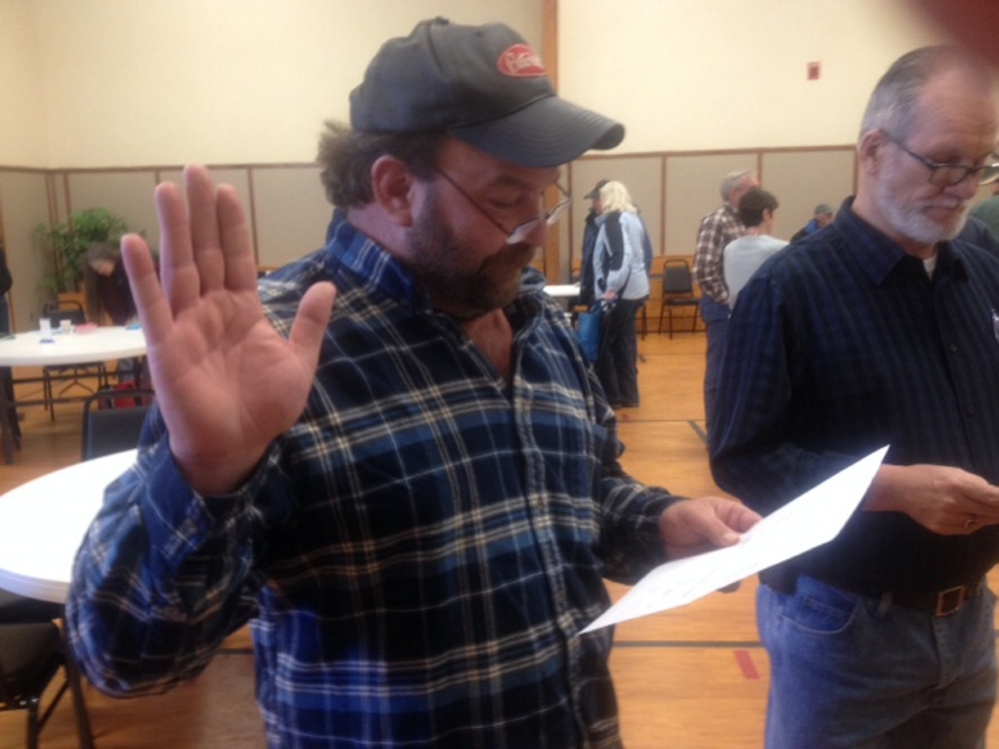 Embden Road Commissioner Michael Witham takes the oath of office Saturday following his re-election in Town Meeting voting. Newly elected Selectman Wayne McLaughlin, right, awaits his turn to take the oath.