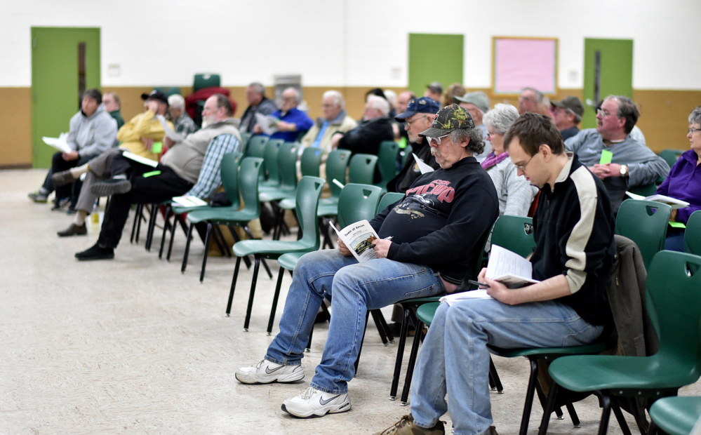 Anson residents read through the many articles to be voted on Saturday during the annual town meeting at Carrabec High School in Anson.