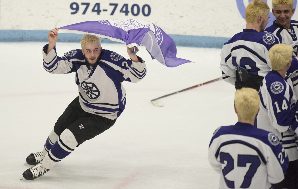 Waterville forward Cody Pellerin circles fellow teammates with the a school flag after they defeated Old Town/Orono 6-5 in overtime in the Class B championship game Tuesday night in Orono