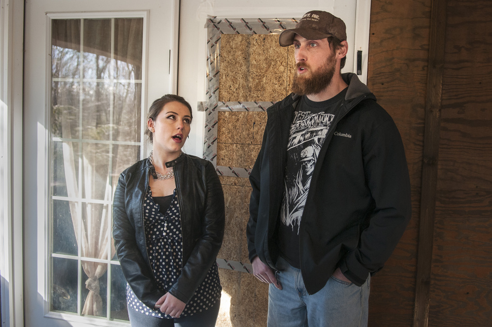 Standing in front of the boarded-over broken window of their front door, Lindsey Levasseur, left, and Trevor Whitney tell the story of an early morning home invasion Wednesday at their apartment in Richmond.
