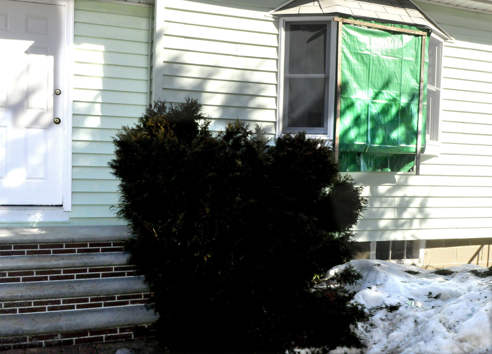A tarp covers a broken front window at the Audrey Hewett residence at 47 Lyons Road in Sidney on Monday. Police allege a male intruder, Dreaquan Foster, was confronted Sunday evening by Hewett's son Eric, who was injured when struck by a blunt object. In the scuffle Eric Hewett shot Foster in the chest.