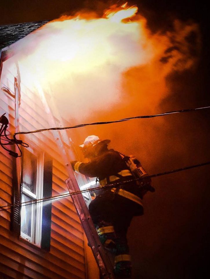 Monmouth firefighter Josh Reny uses a ground ladder to fight a fire that burned a single-family Tuesday night in home in Monmouth.