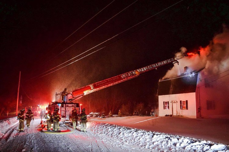 Winthrop Fire Department's truck 3 shoots a stream of water Tuesday into the attic through an opening in the roof of a home on Route 135 in Monmouth. The home may be total loss.