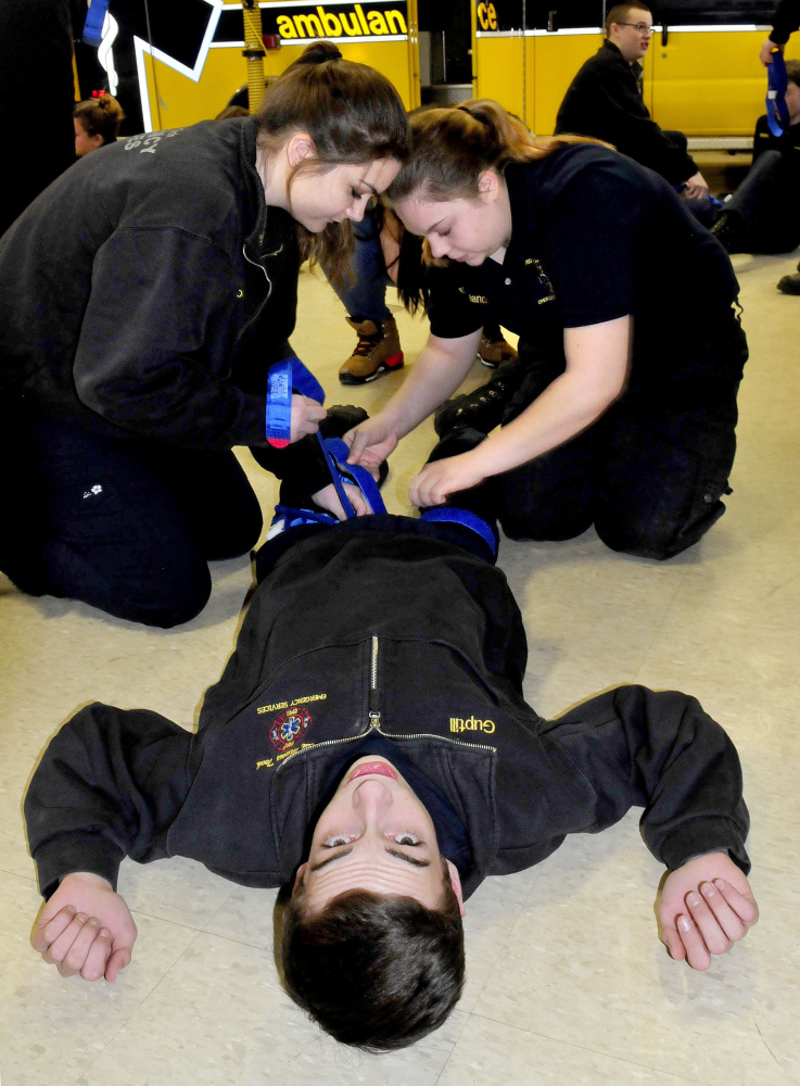 Mid-Maine Technical Center students apply tourniquets to Hunter Guptill on Thursday during training by Homeland Security expert Paul Brooks on stopping bleeding at the school in Waterville. The students are Ashley Leighton, left, and Emily Melancon.