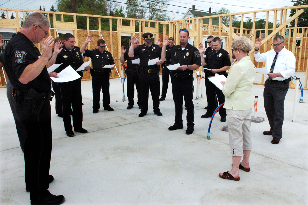 Oakland Town Clerk Jan Porter swears in Oakland police officers and Town Manager Gary Bowman, at right, on May 25, 2016, inside the construction zone of the town's new police station. Oakland police officers voted Friday to unionize with the Maine Association of Police.