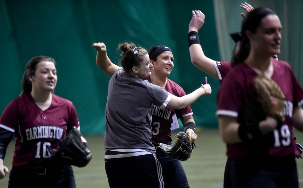 University of Maine Farmington center fielder Kiana Thompson (13), right center, celebrates with teammates after beating the University of Miane at Presque Isle on Saturday at the Sport Dome in Topsham.