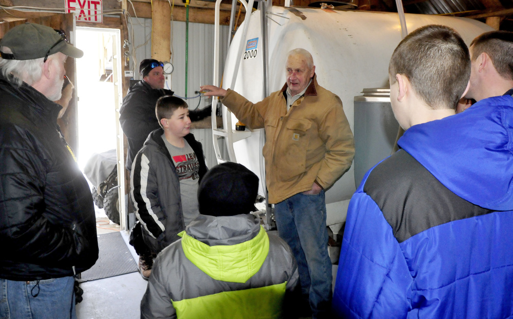 As Jeremy Steeves, background, fills tanks with maple sap, his father, Jack Steeves, conducts a tour of the sugarhouse at Strawberry Hill Farm in Skowhegan on Maine Maple Sunday.