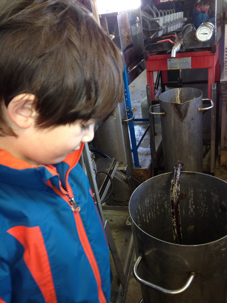 Wyatt Pollard, 6, of Benton, peers into a vat of maple syrup that is being pumped into a 15-gallon barrel Sunday under the watchful eye of Kevin Bacon, owner of Bacon Farm Maple Products in Sidney.