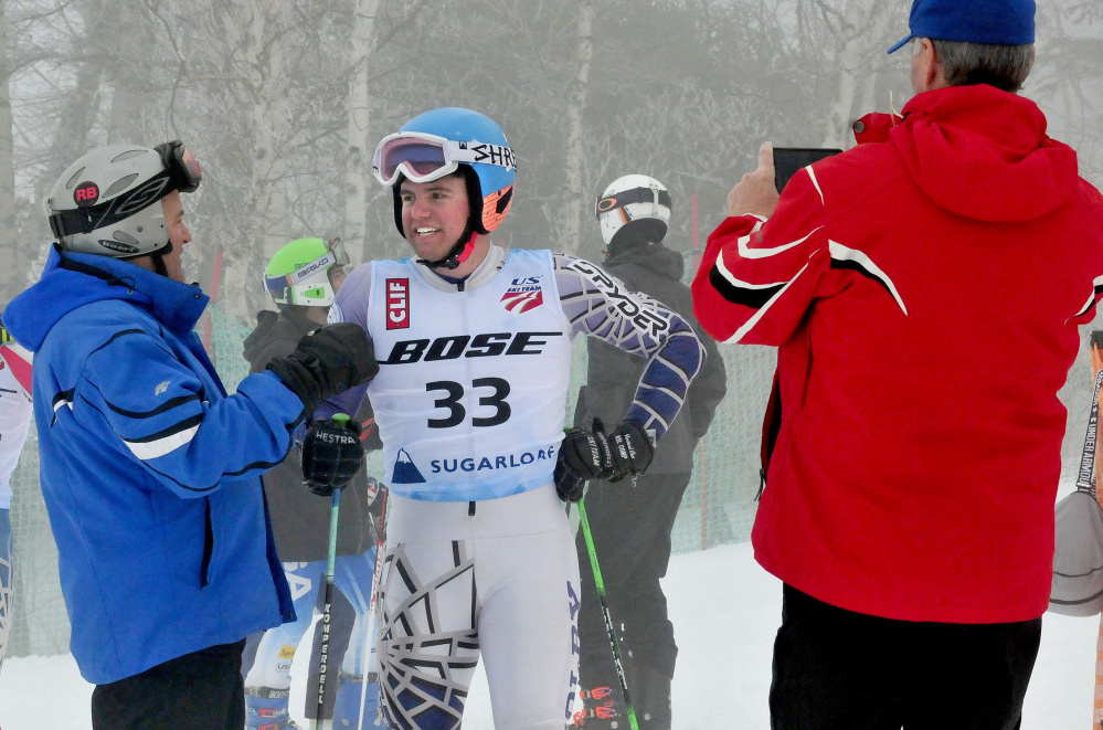Colby student Michael Boardman talks with his father Jeff, left, after competing in a giant slalom race at the U.S. Alpine Championships on Tuesday at Sugarloaf Mountain. At right Bob Haskell, father of competitor Mardi Haskell, photographs the Boardmans.