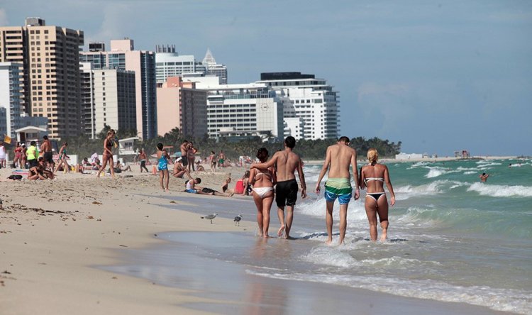 Tourists stroll the beach in Miami on Oct. 5, 2016.  Miami, New York and Los Angeles, being among the most popular destinations for foreign travelers, are especially vulnerable to any tourism declines.