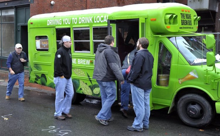 Zach Poole, right, greets tour members as they board the Maine Brew Bus behind the Thirsty Pig for a  2014 tour of two breweries, a meadery, a coffee roaster, a fermenter and distiller over several hours.