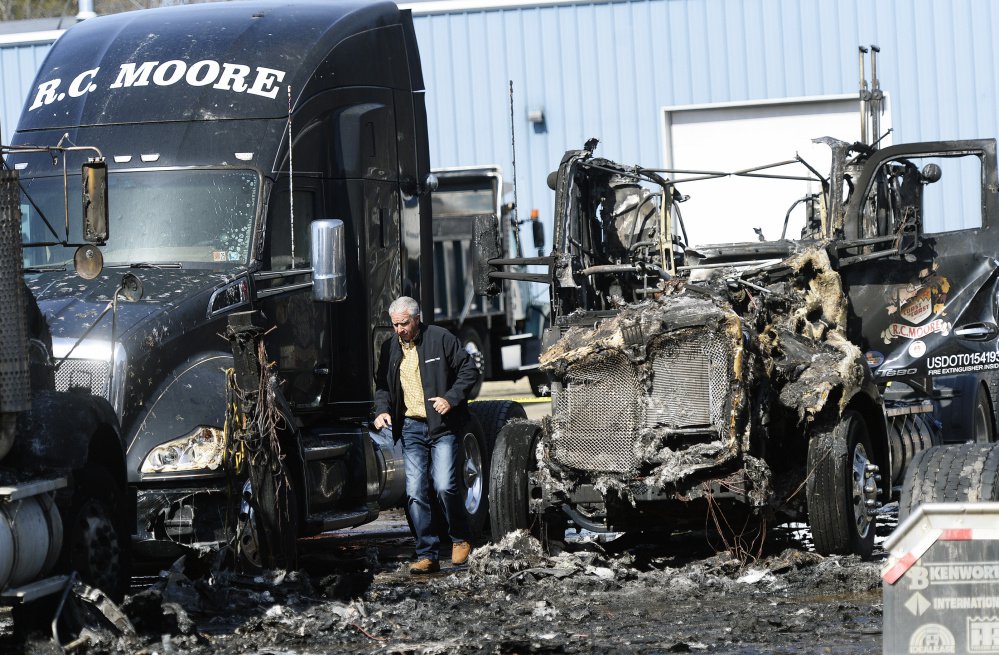 Kelly Moore of R.C. Moore looks over the damage to trucks Monday at the company's depot in Poland. The State Fire Marshal's Office is investigating the coordinated arson fires Sunday night that destroyed six tractor-trailer cabs and damaged two others at the company's facilities in Poland and Scarborough. (Staff photo by Shawn Patrick Ouellette/Staff Photographer)