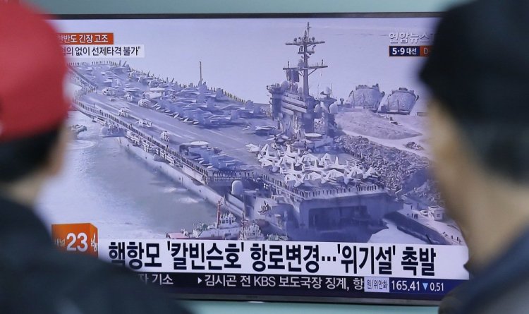 People in Seoul, South Korea, watch a TV news program showing a file image of the USS Carl Vinson aircraft carrier last week. The ship that U.S. officials portrayed as a sign of stepped-up response to North Korea was quietly operating in the Indian Ocean, thousands of miles away.