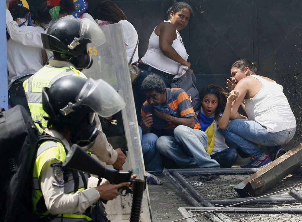Anti-government demonstrators take cover from advancing police officers during protests in Caracas, Venezuela, Wednesday.