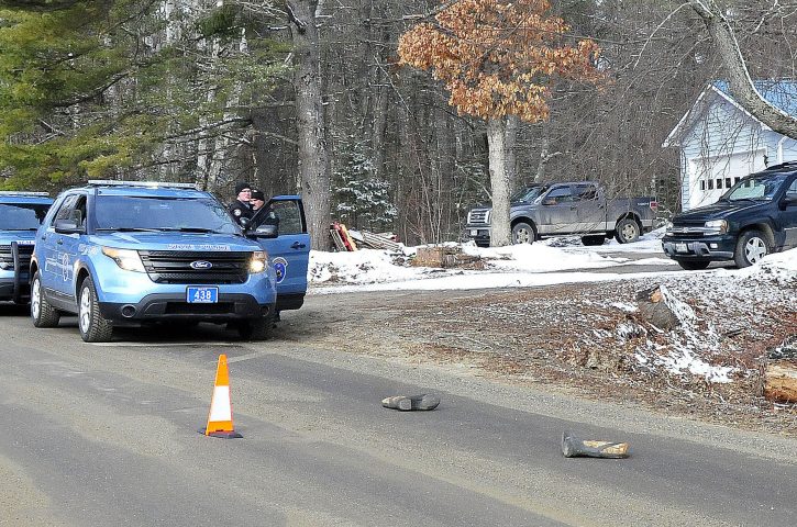 Two Maine State Police troopers consult with each other outside a residence Sunday on Winnecook Road in Burnham while investigating the death of Joyce Wood. A pair of boots lie in the road in foreground.