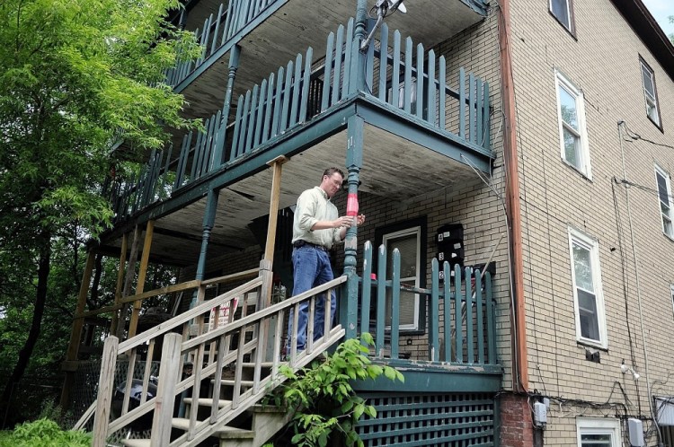 Augusta Code Enforcement Officer Rob Overton tapes a notice indicating the building is unsafe on the deck at 11 State St. in this May 2012 file photo. Tenants in the units were ordered to relocate then, and now city officials might take possession of the property.